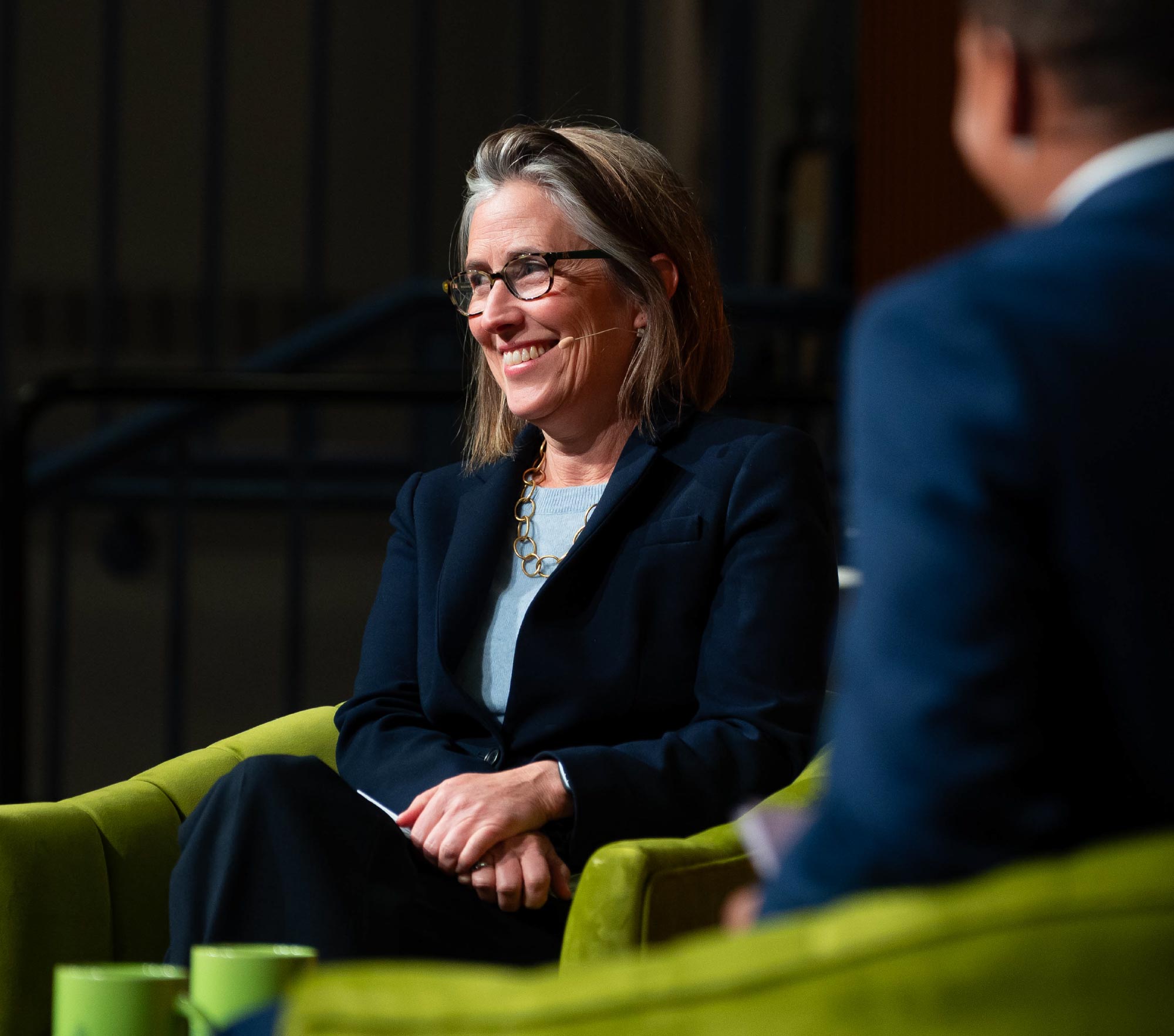 A smiling woman in a blazer speaks at a Colby University discussion panel.