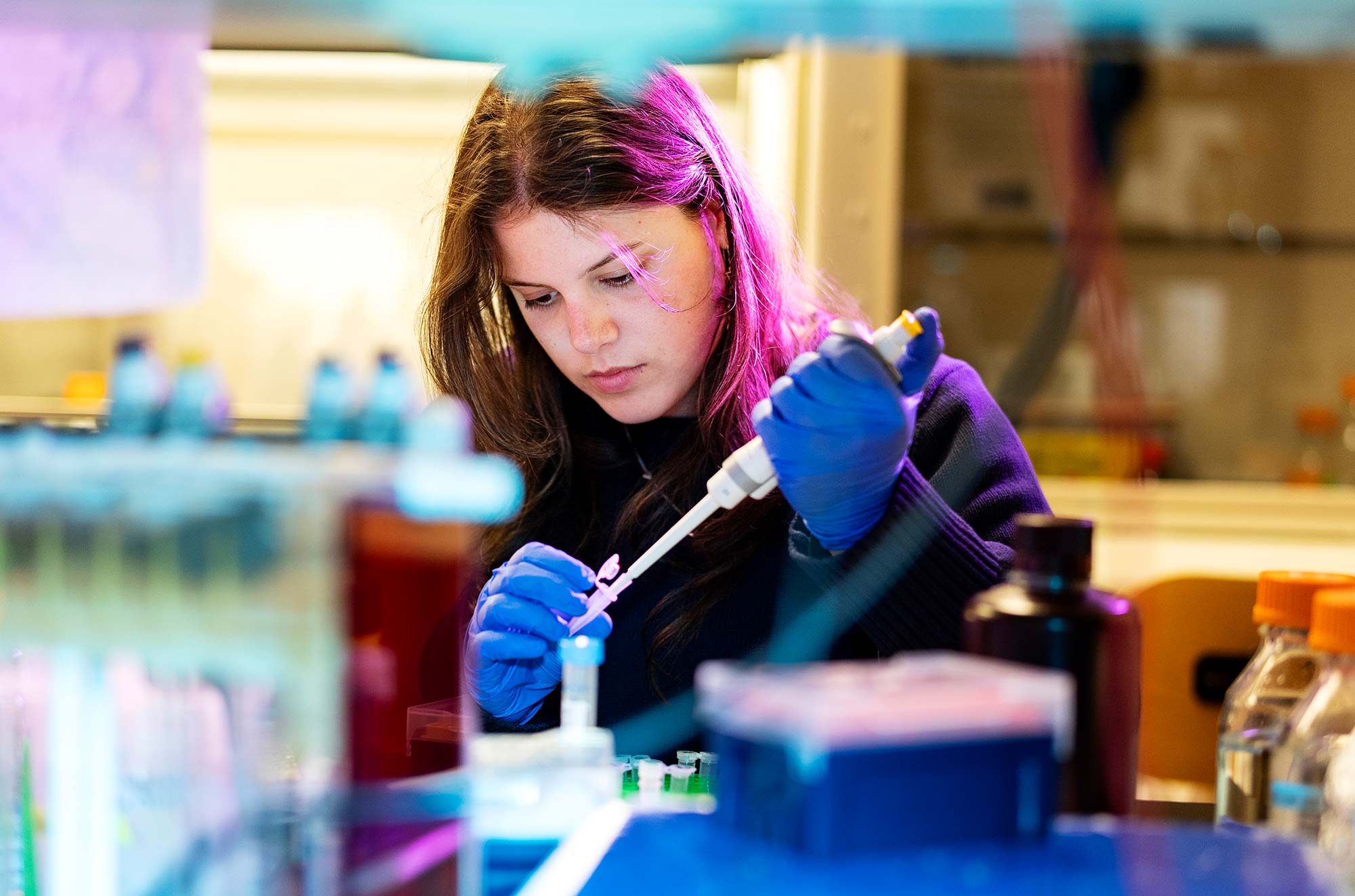 Caitlin Haller, a female student using a handheld micropipette to transfer liquid into small vials in a lab in Arey Life Sciences Building